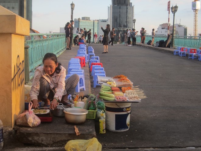 Lúc trước, những người này chỉ bày bán xung quanh dưới chân cầu Mống thì nay, họ chiếm dụng cả mặt cầu phía trên để bán hàng ăn.