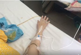 Hình ảnh nữ bệnh nhân nằm trên giường bệnh gõ nhịp theo lời hát Việt Nam quê hương tôi