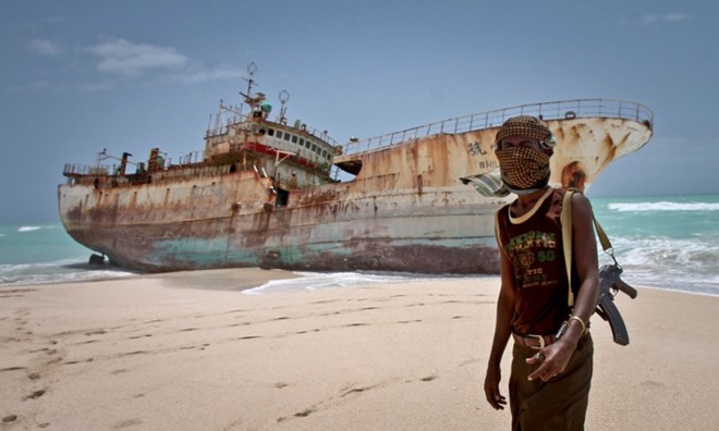 Một tên cướp biển Somalia trước một tàu cá bị bắt giữ hồi năm 2012.