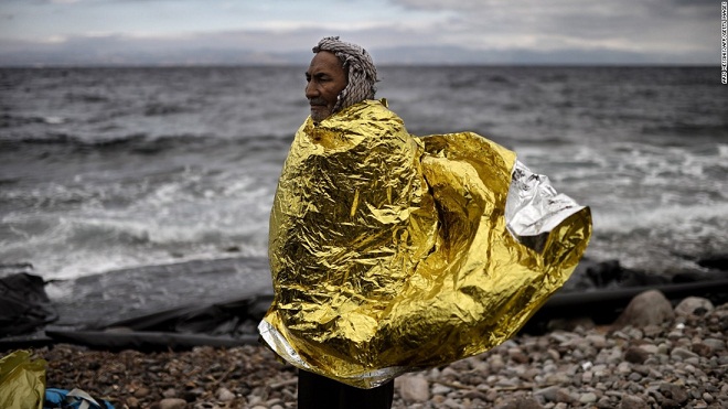 Người đàn ông tị nạn khoác áo che mưa mỏng đứng trên bờ biển Lesbon